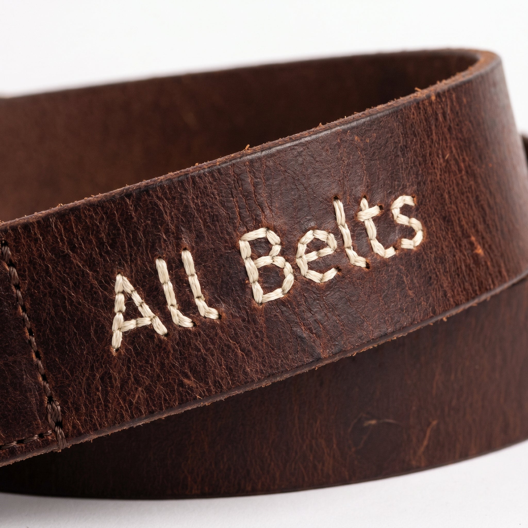 Brown leather belt with 'All Belts' embroidery on a white background