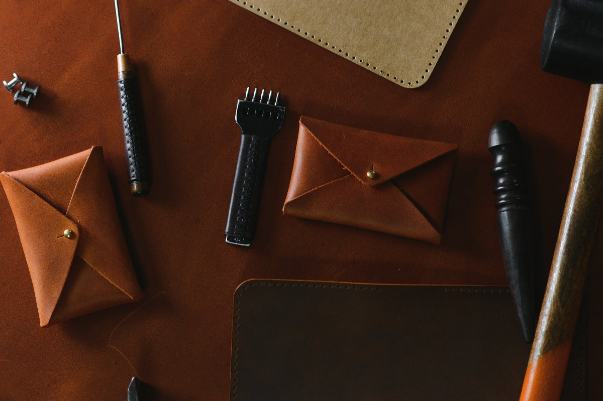 Collection of leather products including wallets and a pen on a brown surface.
